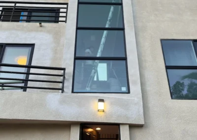 Exterior view of a modern building with large windows, a ladder inside, and two people entering and exiting the bottom door.